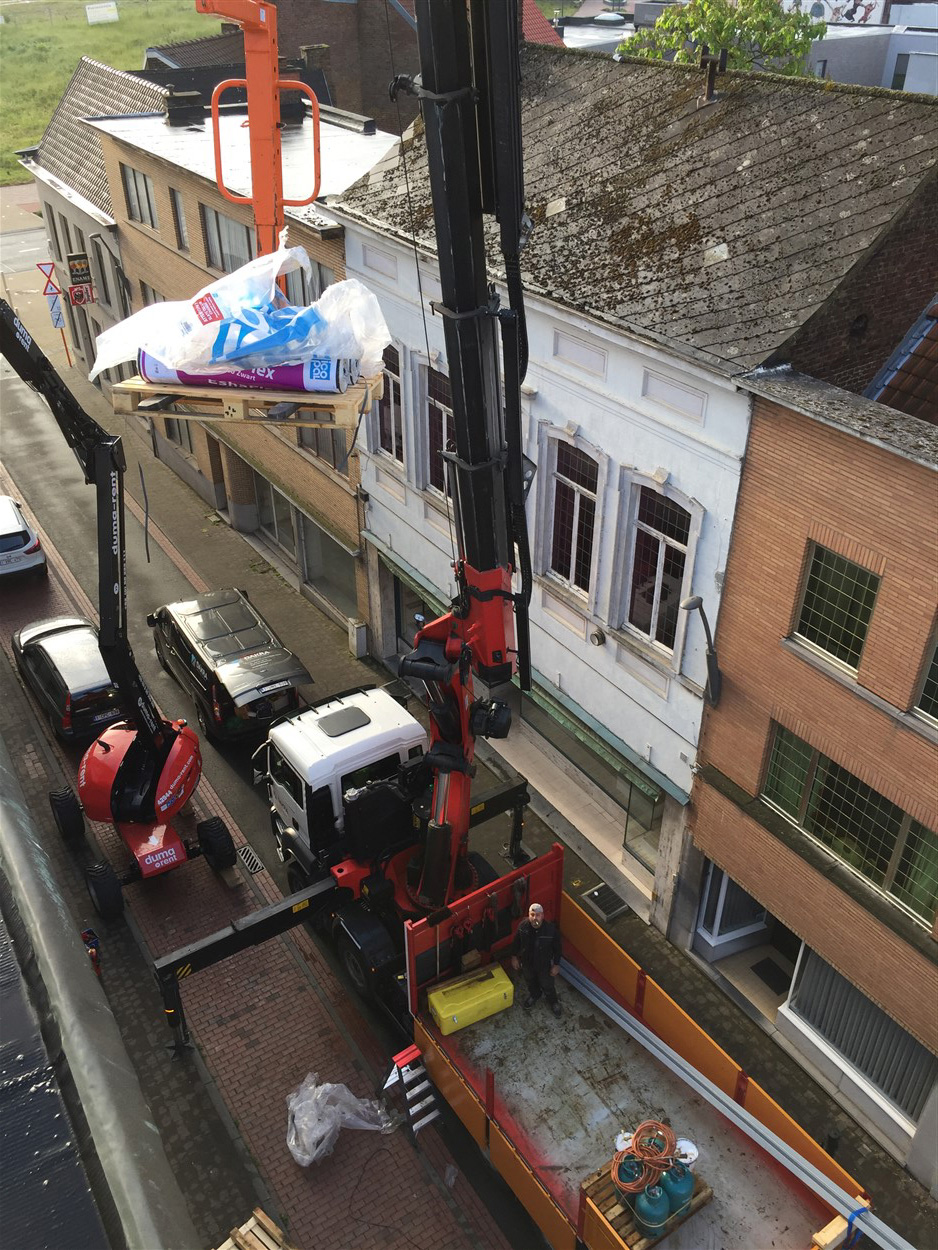 Kraan hijst dakmateriaal naar een woning in renovatie, DAKRA-vrachtwagen op straat