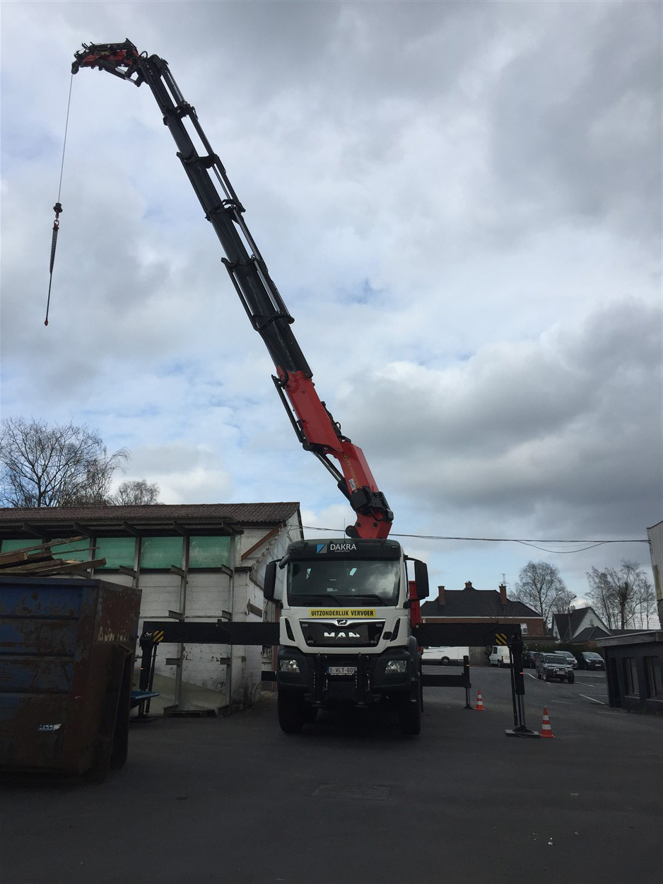 Kraanwagen aan het werk op een dak tussen bedrijfsgebouwen en woningen