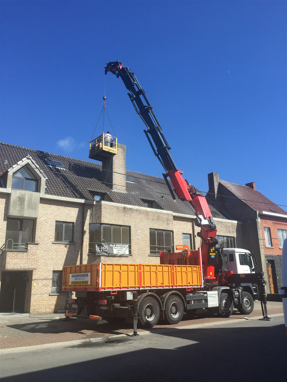 Kraanarm in actie boven een bouwplaats met de last aan de hijskabel